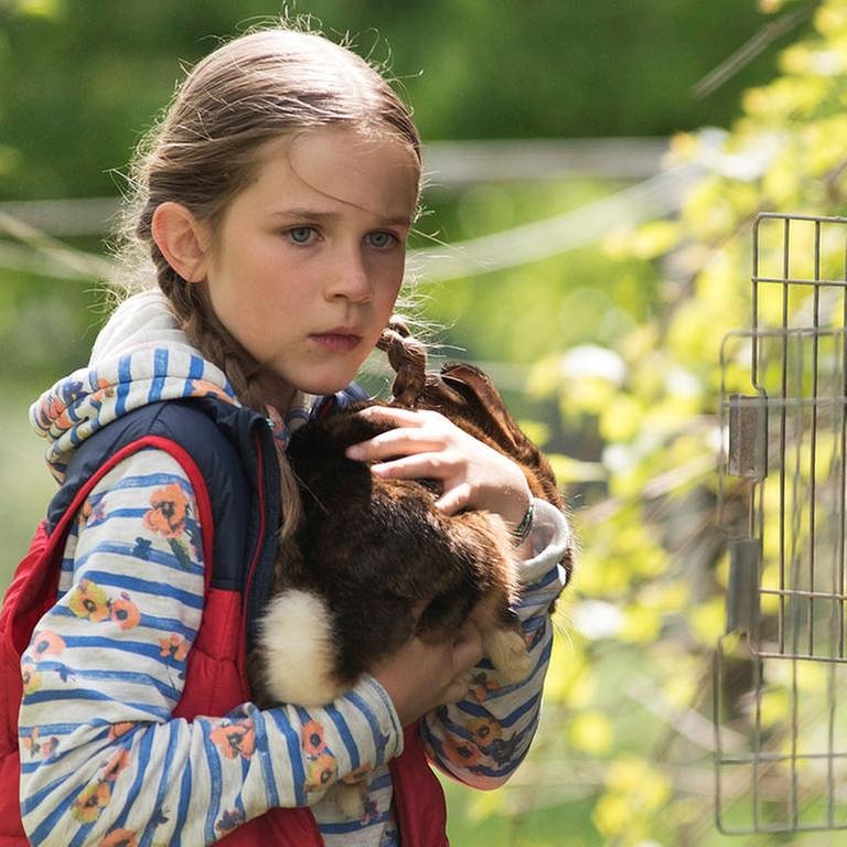Lucy aus der Serie "Tiere bis unters Dach" mit einem Kanichen auf dem Arm