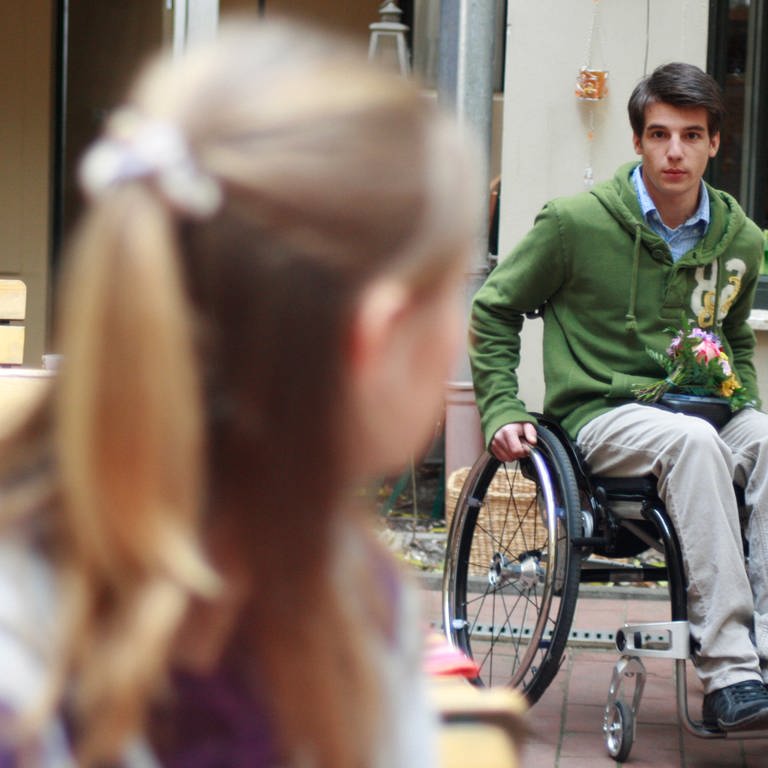 Peter kommt mit seinem Rollstuhl in den Innenhof einer Gaststätte. (Foto: SWR, MDR)